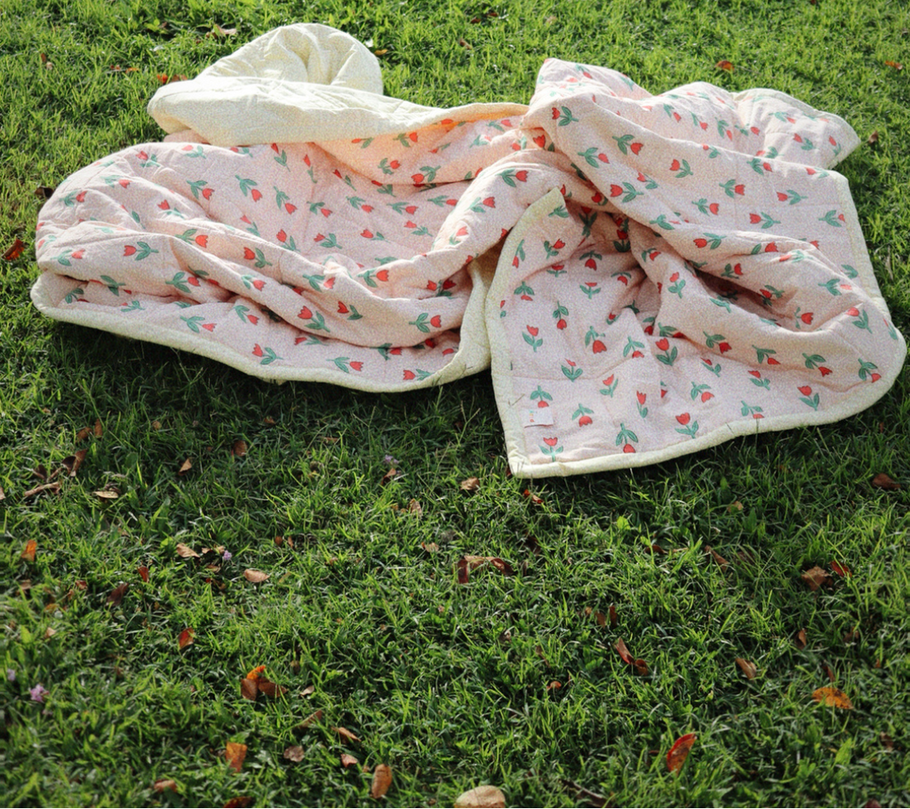 Floral-patterned blanket on grass with 'Play' text
