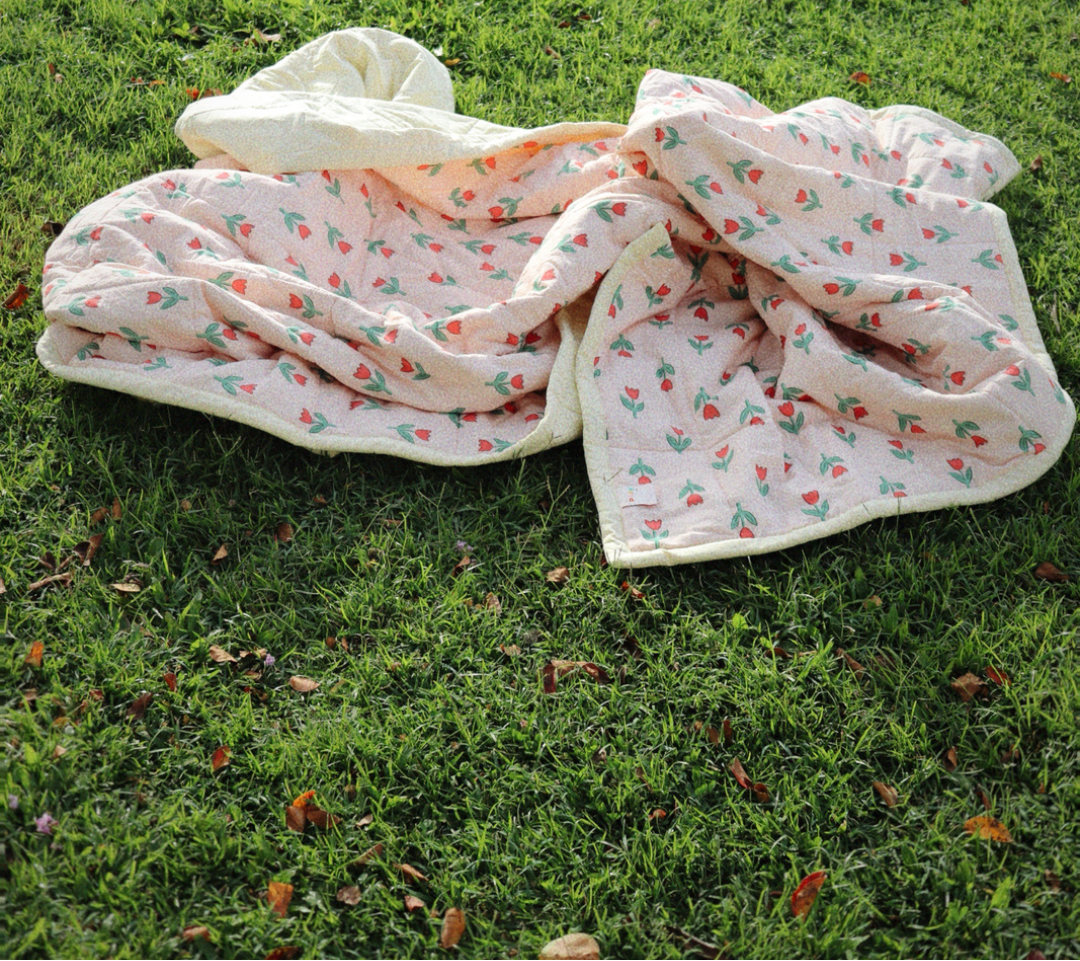 Floral-patterned blanket on grass with 'Play' text